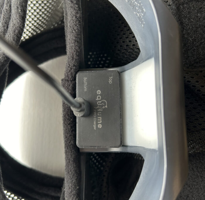 Equilume Pro Wireless charging pad attached to the USB cable is shown attached to the inside of the Equilume Pro Light Mask cup ready to charge.